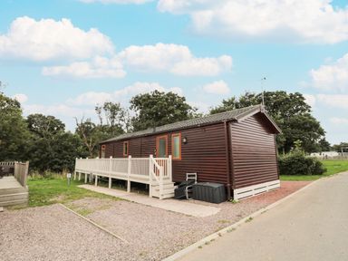 An exterior view of a wooden lodge with a white railing and a small set of stairs at Number 43 Burnside Lodge in Felton