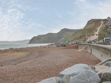 A pebble beach with a seawall and hills in the background at West Bay Holiday Home in West Bay