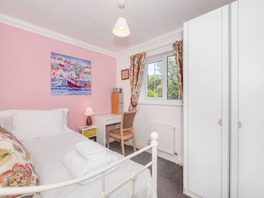 A bedroom with a single bed a desk a chair a window and a wardrobe at West Bay Holiday Home in West Bay