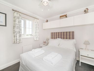 A bedroom with a double bed towels on the bed and wall cabinets at West Bay Holiday Home in West Bay