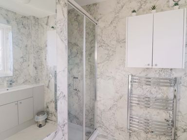 A bathroom with a shower and sink at West Bay Holiday Home in West Bay