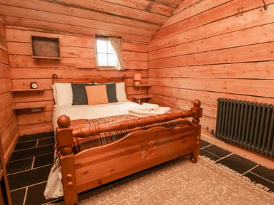 A bedroom with a wooden bed and pillows in a log cabin at Y Caban Pontfadog near Llangollen