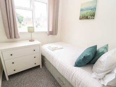 A small bedroom with a single bed white chest of drawers and a window with curtains at 17 Sands Close Broadway