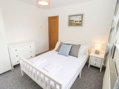 A bedroom with a white bed frame a dresser nightstand and a lamp at 17 Sands Close in Broadway