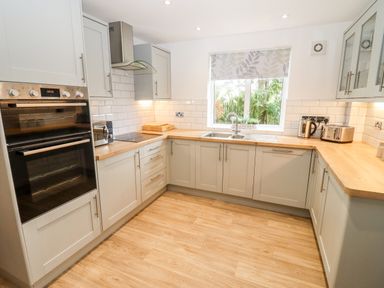 A kitchen with wooden countertops white cabinets a window over the sink and appliances at 17 Sands Close Broadway