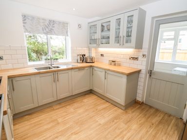 A kitchen with wooden countertops gray cabinets and a window at 17 Sands Close in Broadway