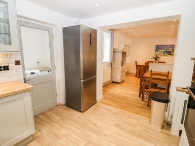 A kitchen with wood flooring a stainless steel refrigerator and a wooden dining table at 17 Sands Close Broadway