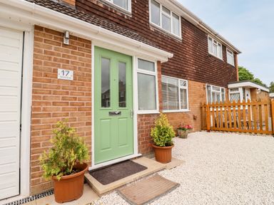 Exterior of house with green front door two potted plants gravel yard and wooden fence at 17 Sands Close in Broadway