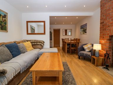 A living room with a sofa, coffee table, armchair, lamp, and dining table at 17 Sands Close in Broadway