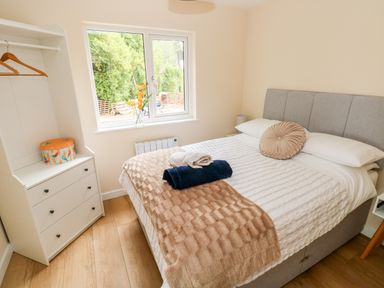 A bedroom with a double bed and bedside tables near a window at Caldey Lodge in Manorbier