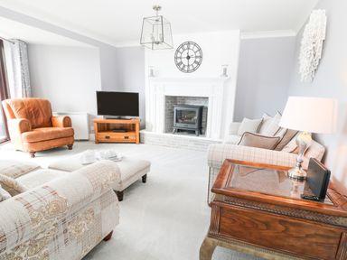 A living room with armchairs a television and a fireplace at 12 Claremont Falls in Polperro