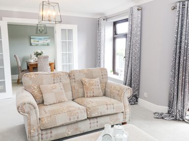 A living room with patterned sofa coffee table and grey curtains at 12 Claremont Falls Polperro