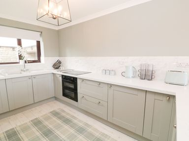 A kitchen with gray cabinets white countertops a window and small appliances at 12 Claremont Falls in Polperro