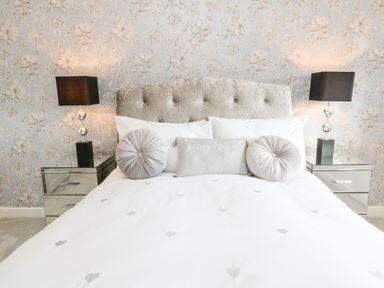 A bed with a tufted headboard and pillows with two bedside tables with lamps at 12 Claremont Falls in Polperro
