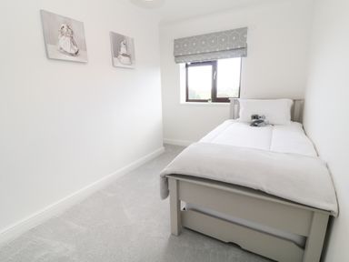A bedroom with a single bed two stuffed animals on the bed and two paintings on the wall at 12 Claremont Falls in Polperro