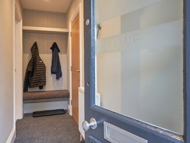 An entryway with coats hanging on hooks and a bench at Lower Sheriff's Place Windermere