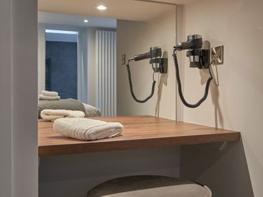 A bathroom counter with folded towels and a wall-mounted hairdryer at Lower Sheriff's Place in Windermere