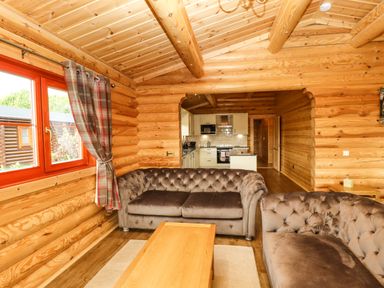 A living room with two brown sofas a wooden coffee table and a window with plaid curtains at Oak Lodge in Greetham Rutland