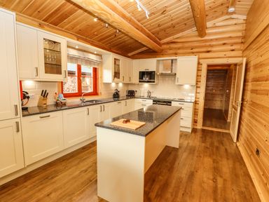 A kitchen with wooden walls and ceiling white cabinets and a central island at Oak Lodge in Greetham Rutland