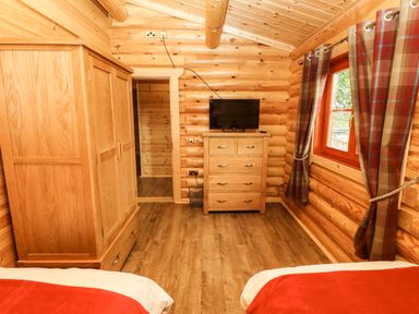 A bedroom with wooden wardrobe chest of drawers and a television at Oak Lodge in Greetham Rutland