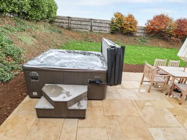A backyard with a hot tub and patio furniture including a table and chairs at Oak Lodge in Greetham Rutland