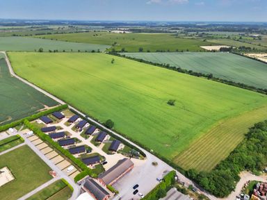 Aerial view of fields with a cluster of buildings and parked cars at Oak Lodge in Greetham Rutland