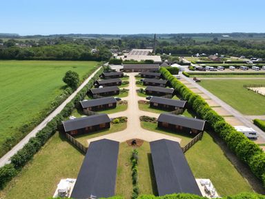 Aerial view of a row of cabins with pathways and green fields surrounding them at Oak Lodge in Greetham Rutland