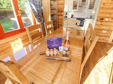 A wooden dining table with eggs chocolates tea pods and a bottle in a kitchen at Holly Lodge in Greetham Rutland