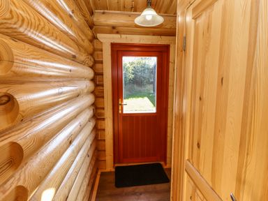 A wooden hallway with a red door and a light fixture at Pine Lodge in Greetham Rutland
