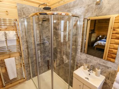 A bathroom with glass shower cubicle sink with soap dispenser and towel rack at Pine Lodge in Greetham Rutland