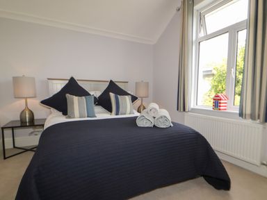 A bedroom with a bed with pillows and rolled towels beside a window at Robin Hill in Duporth near St Austell