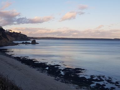 A coastal scene with cliffs sandy shore and calm sea at Robin Hill in Duporth near St Austell