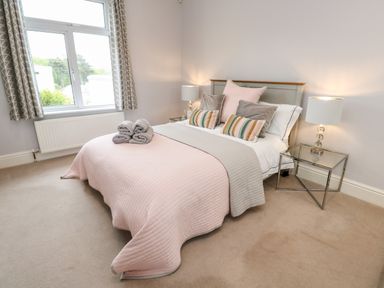 A bedroom with a bed with folded towels bedside lamps and a window at Robin Hill in Duporth near St Austell