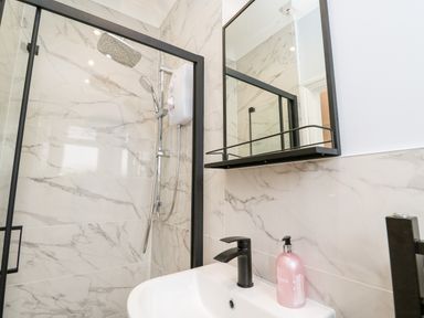 A bathroom with a shower area a sink with a faucet and a mirror above the sink at Robin Hill in Duporth near St Austell