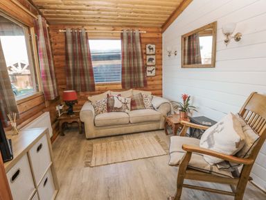A living room with a beige sofa and pillows wooden rocking chair wooden side tables and curtains at Ingram in Longframlington