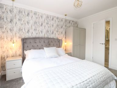 A bedroom with a bed bedside tables a wardrobe and a door at Harbour Place in Wells-Next-The-Sea