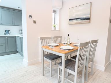 A dining table set for four near a kitchen with blue cabinets at Harbour Place in Wells-Next-The-Sea