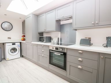 A kitchen with grey cabinets a washing machine an oven a microwave a toaster and a kettle at Harbour Place in Wells-Next-The-Sea