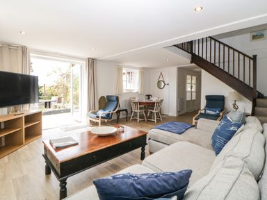 A living room with a sofa table chairs and TV near stairs at The Holt in Harcombe near Sidford