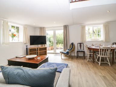 A living and dining area with a sofa coffee table TV and dining table with chairs at The Holt in Harcombe near Sidford