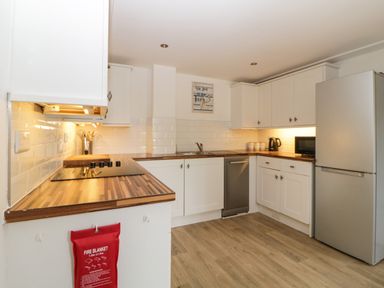 A kitchen with white cabinets wooden countertops a stove a dishwasher a refrigerator a microwave and a kettle at The Holt in Harcombe near Sidford