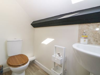 A bathroom with a toilet wooden seat hand wash on a sink and toilet paper holder at The Holt in Harcombe near Sidford