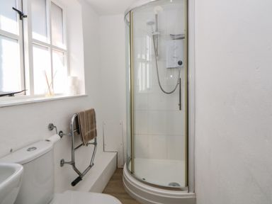 A bathroom with a shower enclosure a toilet a towel rack and a window at The Holt in Harcombe near Sidford