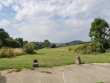 A grassy field with trees and hills in the background at The Holt in Harcombe near Sidford