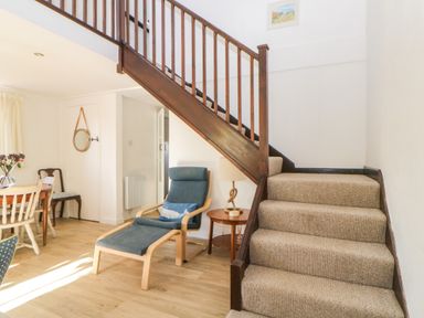 A staircase with carpet next to a wooden chair with blue cushion and a side table with lamp at The Holt in Harcombe near Sidford