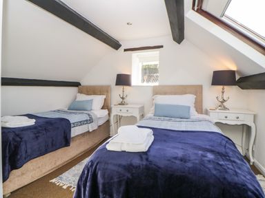 A bedroom with two single beds side by side with navy blue blankets and white pillows at The Holt in Harcombe near Sidford