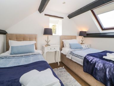 A bedroom with two single beds with blue and white bedding and bedside tables with lamps at The Holt in Harcombe near Sidford