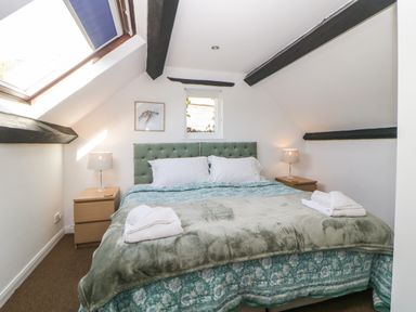 A bedroom with a double bed green headboard bedside tables lamps and a skylight window at The Holt in Harcombe near Sidford