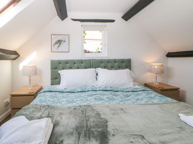 A bedroom with a double bed two bedside tables with lamps and a small window above the bed at The Holt in Harcombe near Sidford