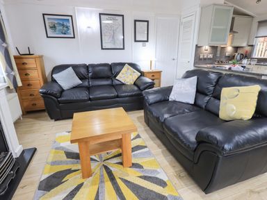 A living room with two black leather sofas a wooden coffee table and colorful rug at Lavender Lodge Applethwaite 4 Limefitt Park near Windermere
